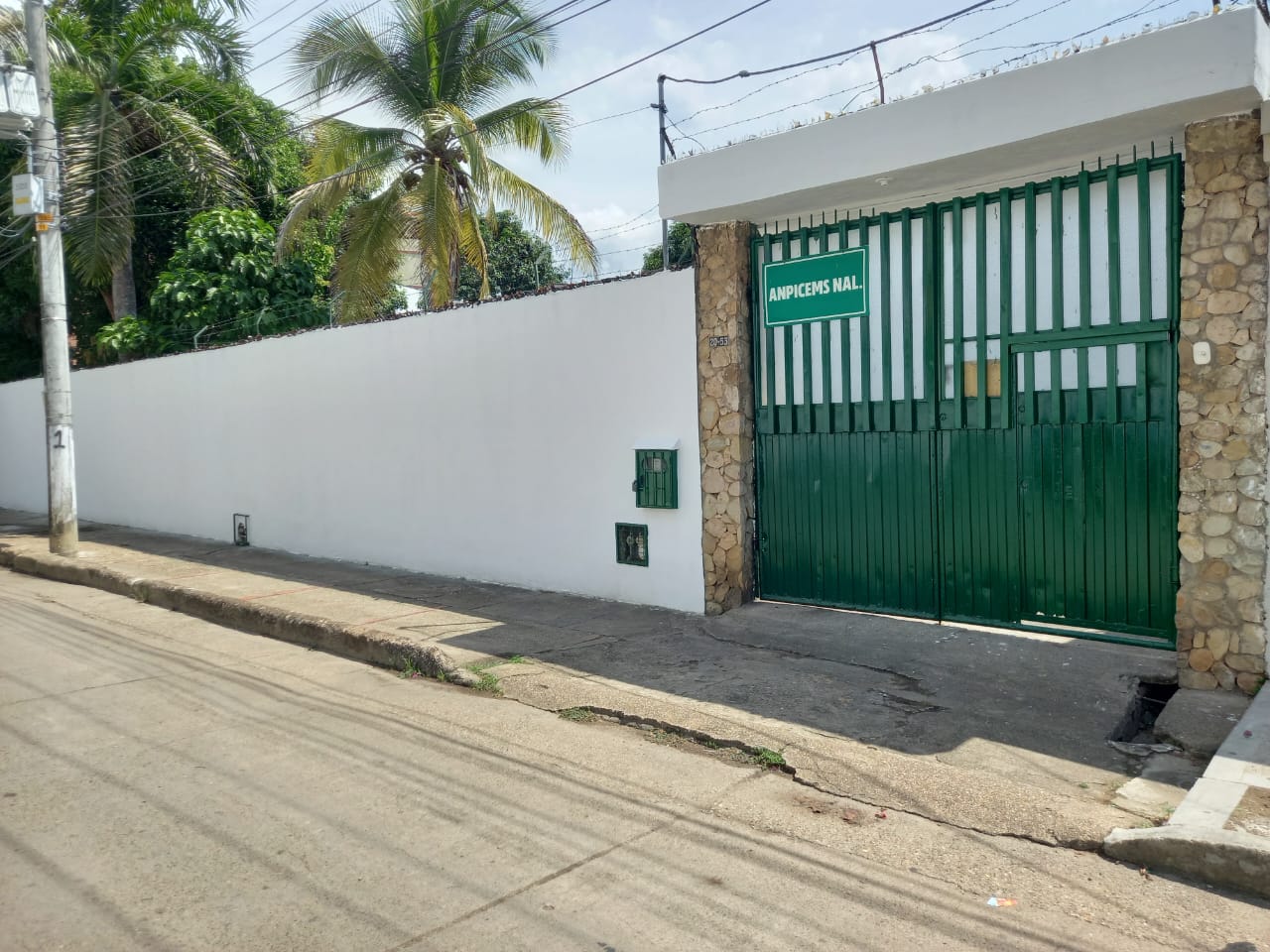 Fachada de la finca con portón verde y muro blanco